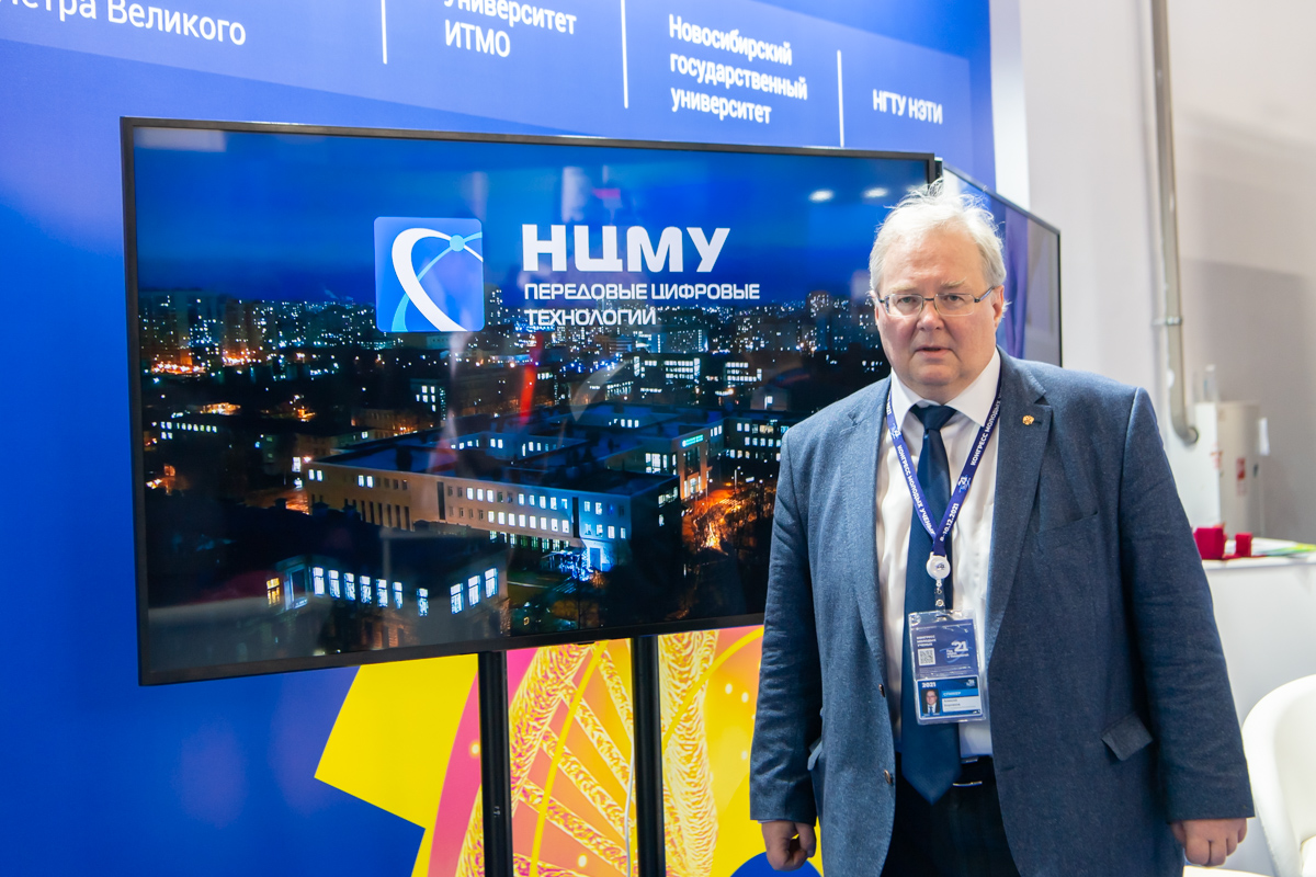 Алексей Боровков на стенде СПбПУ, где демонстрируются видеоролики о деятельности, проектах и результатах лабораторий и центров, входящих в НЦМУ «Передовые цифровые технологии» 